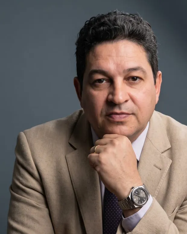 Dr. Carlos Fabiano de Oliveira, de blazer bege, com a mão apoiada no queixo