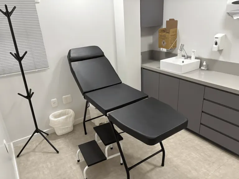 Sala de procedimentos do consultório, com maca reclinável e bancada